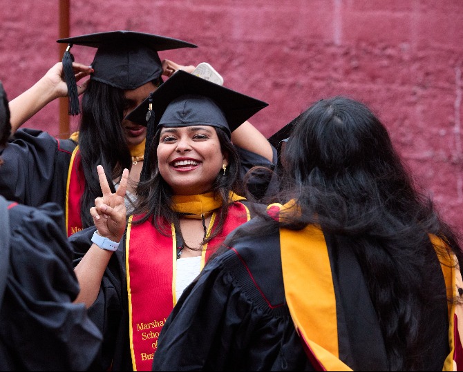 Woman doing the peace hand sign and smiling at graduation